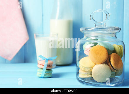 Sanfte bunte Makronen in Gläsern, Milch Glas und Handtuch auf Farbe holztisch Hintergrund Stockfoto