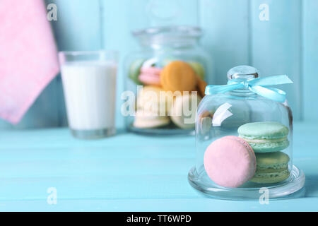 Sanfte bunte Makronen in Glas jell jar, Milch Glas und Handtuch auf Farbe holztisch Hintergrund Stockfoto