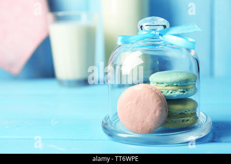 Sanfte bunte Makronen in Glas jell jar, Milch Glas und Handtuch auf Farbe holztisch Hintergrund Stockfoto