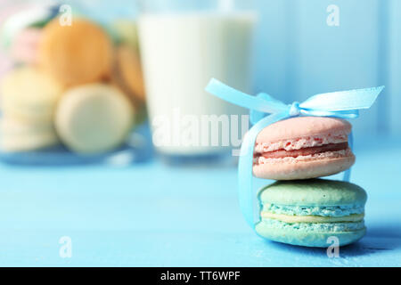 Sanfte bunte Makronen in Gläsern, Milch Glas und Handtuch auf Farbe holztisch Hintergrund Stockfoto