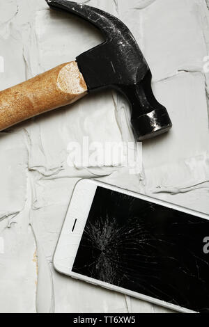 Gebrochene iPhone mit Hammer auf Stein Hintergrund Stockfoto