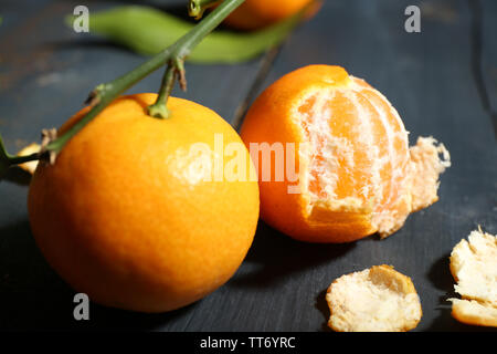 Saftige reife Tangerinen mit Blättern auf hölzernen Tisch Stockfoto