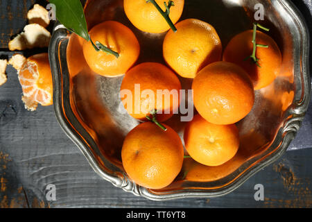 Saftige reife Tangerinen mit Blättern auf hölzernen Tisch Stockfoto