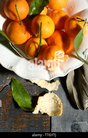 Saftige reife Tangerinen mit Blättern auf hölzernen Tisch Stockfoto