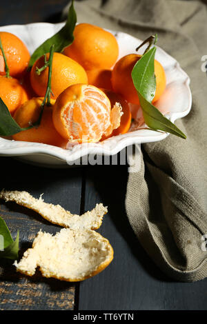 Saftige reife Tangerinen mit Blättern auf hölzernen Tisch Stockfoto