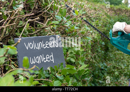 Freiwillige für die Gartenarbeit benötigt. Freiwillige den Satz 'Erforderlich' ist auf eine Schiefertafel geschrieben. Stockfoto