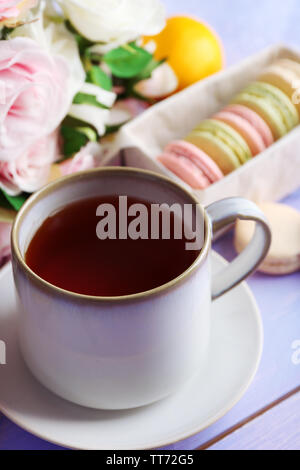 Bunte Makronen mit Tasse Tee auf hölzernen Hintergrund Stockfoto