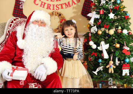 Santa Claus, die Gegenwart zu schlafen kleine süße Mädchen Weihnachtsbaum zu Hause Stockfoto