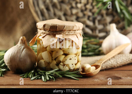 Konserven Knoblauch in Glas, Korbweide matte und Rosmarin Zweige auf Holz- Hintergrund Stockfoto