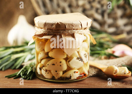 Konserven Knoblauch in Glas, Korbweide matte und Rosmarin Zweige auf Holz- Hintergrund Stockfoto