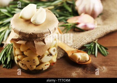 Konserven Knoblauch in Glas, Korbweide matte und Rosmarin Zweige auf Holz- Hintergrund Stockfoto