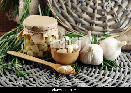 Konserven Knoblauch in Glas und Rosmarin Zweige Wicker matte Hintergrund Stockfoto