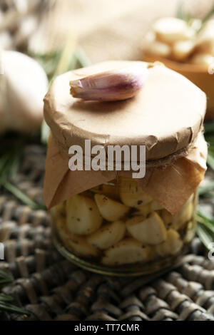 Konserven Knoblauch in Glas und Rosmarin Zweige Wicker matte Hintergrund Stockfoto