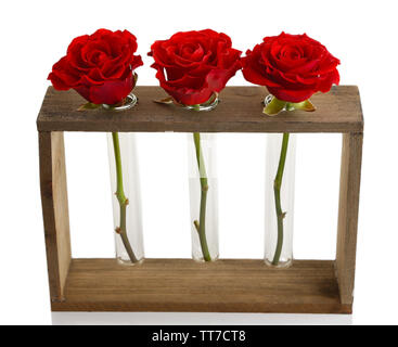 Drei frische Rosen in Glasvase und stand aus Holz isoliert auf weißem Stockfoto