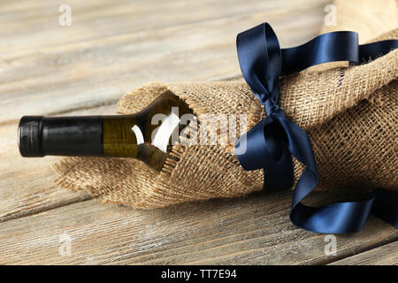 Flasche Wein in sackleinen Tuch auf Holzbohlen Hintergrund gewickelt Stockfoto
