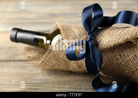 Flasche Wein in sackleinen Tuch auf Holzbohlen Hintergrund gewickelt Stockfoto