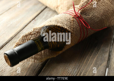 Flasche Wein in sackleinen Tuch auf Holzbohlen Hintergrund gewickelt Stockfoto