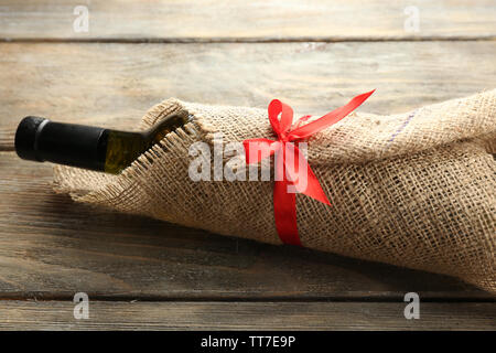Flasche Wein in sackleinen Tuch auf Holzbohlen Hintergrund gewickelt Stockfoto