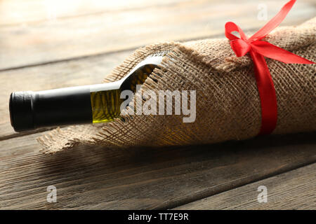 Flasche Wein in sackleinen Tuch auf Holzbohlen Hintergrund gewickelt Stockfoto