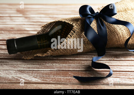 Flasche Wein in sackleinen Tuch auf Holzbohlen Hintergrund gewickelt Stockfoto