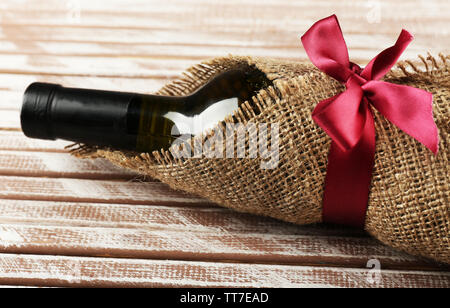 Flasche Wein in sackleinen Tuch auf Holzbohlen Hintergrund gewickelt Stockfoto