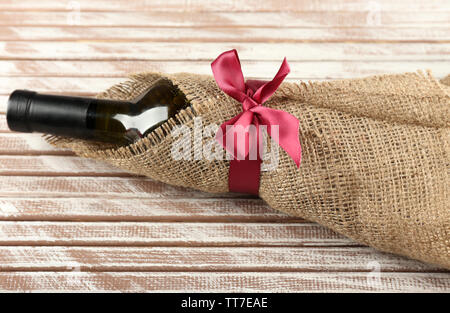 Flasche Wein in sackleinen Tuch auf Holzbohlen Hintergrund gewickelt Stockfoto