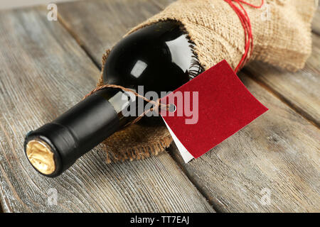 Flasche Wein in sackleinen Tuch auf Holzbohlen Hintergrund gewickelt Stockfoto