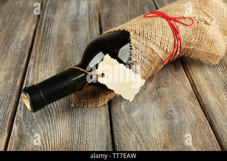 Flasche Wein in sackleinen Tuch auf Holzbohlen Hintergrund gewickelt Stockfoto