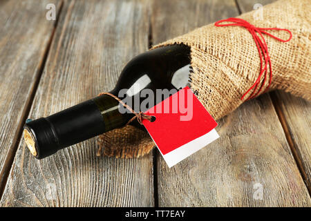 Flasche Wein in sackleinen Tuch auf Holzbohlen Hintergrund gewickelt Stockfoto