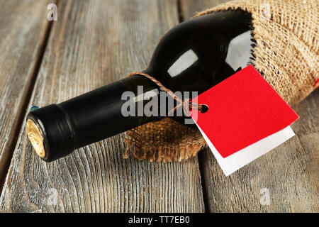 Flasche Wein in sackleinen Tuch auf Holzbohlen Hintergrund gewickelt Stockfoto