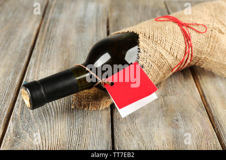 Flasche Wein in sackleinen Tuch auf Holzbohlen Hintergrund gewickelt Stockfoto