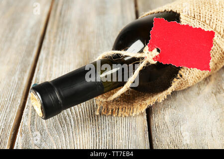 Flasche Wein in sackleinen Tuch auf Holzbohlen Hintergrund gewickelt Stockfoto