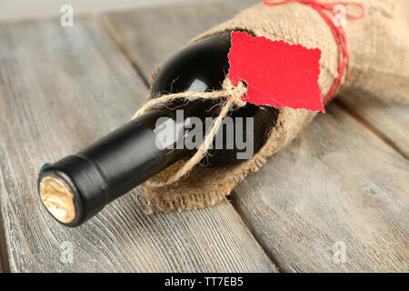 Flasche Wein in sackleinen Tuch auf Holzbohlen Hintergrund gewickelt Stockfoto