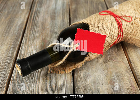 Flasche Wein in sackleinen Tuch auf Holzbohlen Hintergrund gewickelt Stockfoto