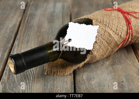 Flasche Wein in sackleinen Tuch auf Holzbohlen Hintergrund gewickelt Stockfoto