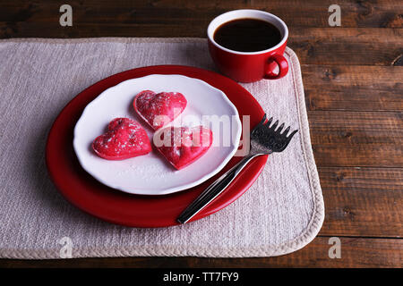 Cookies in Form von Herzen in der Platte mit Tasse Kaffee auf Serviette, auf rustikalen hölzernen Planken Hintergrund Stockfoto
