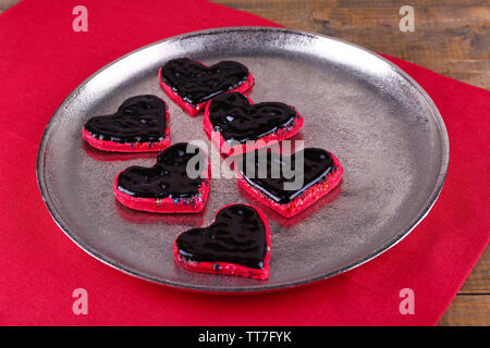 Cookies in Form von Herzen fallen Schokolade auf Metall Tablett mit Serviette auf hölzernen Tisch Hintergrund Stockfoto
