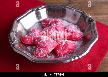 Cookies in Form von Herzen auf Metall Fach und Serviette auf hölzernen Tisch Hintergrund Stockfoto