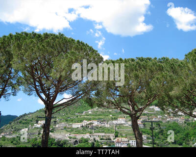 Häuser am Berg mit Touristen und Regenschirm PINIEN in Ravello, Amalfi ROM, ITALIEN. Stockfoto