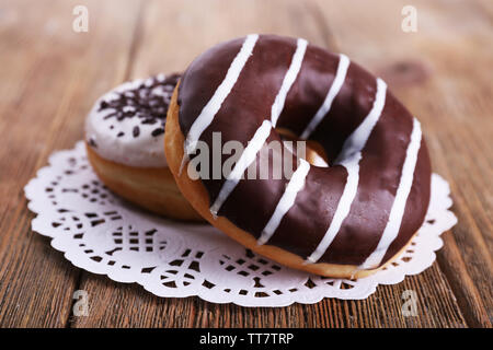 Delicious Doughnuts mit Zuckerglasur auf Spitze Deckchen auf hölzernen Hintergrund Stockfoto