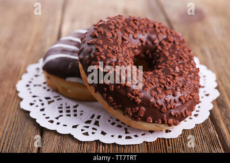 Delicious Doughnuts mit Zuckerglasur auf Spitze Deckchen auf hölzernen Hintergrund Stockfoto
