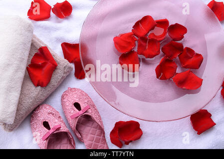 Spa Schüssel mit Wasser, Rosenblüten, Handtuch und Badeschuhe auf hellen Hintergrund. Konzept der Pediküre oder Natural Spa Behandlung Stockfoto