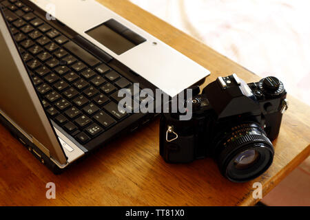 Foto von einem Laptop und einem Handbuch, 35mm Film Kamera auf einem Tisch in einem Schlafzimmer Stockfoto