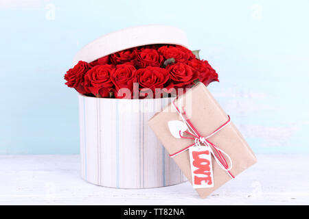 Blumenstrauß aus roten Rosen in Textil- Box mit auf Holz- Hintergrund Stockfoto