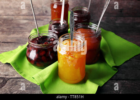 Gläser leckere Marmelade mit Serviette auf Holz- Hintergrund Stockfoto