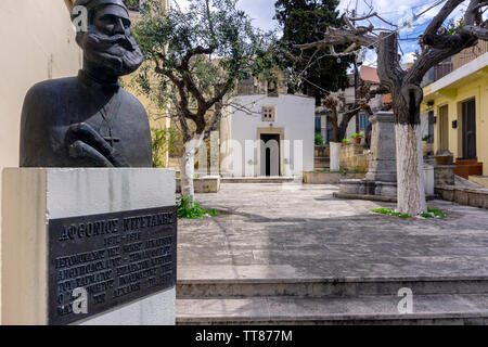 Chersonissos, Kreta/Griechenland. Die "Heilig-Kreuz-Kapelle" in Archanes Stadt. Stein Brunnen im Innenhof, die Statue eines kretischen Held Stockfoto