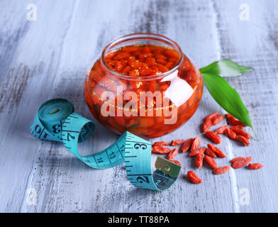 Goji Beeren in Glasschale mit Maßband und Blätter auf Farbe holztisch Hintergrund Stockfoto