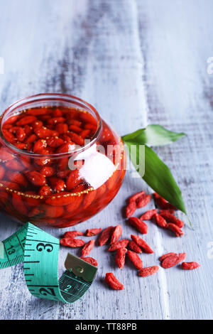 Goji Beeren in Glasschale mit Maßband und Blätter auf Farbe holztisch Hintergrund Stockfoto