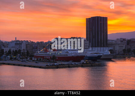 Der Hafen von Piräus, Attika/Griechenland. Bunte sunrise mit feurigen Himmel über dem Hafen von Piräus und Stadt. Fahrgastschiffe haben am Jetty angedockt Stockfoto