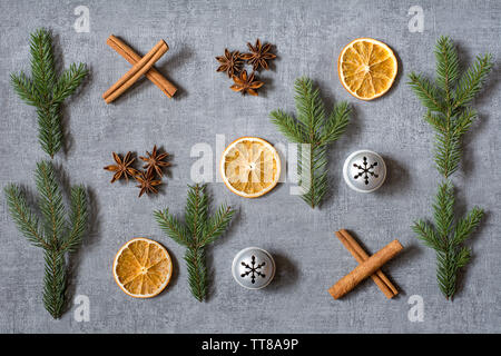 Weihnachten Nullen und Kreuze deco mit getrockneten Orangen, cinamon aniseeds, Sticks, Tannenbaum, Zweige und silbernen Glocken auf grauem Hintergrund Stockfoto